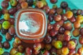 Glass of acerola juice and fresh acerola fruits on a wooden surface