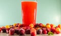 Glass of acerola juice and fresh acerola fruits on a wooden surface