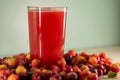 Glass of acerola juice and fresh acerola fruits on a wooden surface