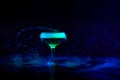 Glass with alcohol cocktail, martini with smoke foam against dark background with neon light. Bartender