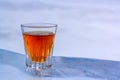 A glass of alcohol stands on an ice plate on a blurry light background. Royalty Free Stock Photo