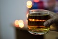 a glass of alcohol whisky held in hand with background blur bokeh lights Royalty Free Stock Photo