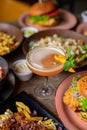 Glass of alcoholic cocktail with mint and orange decor on table full of delicious food. Salad, fries, burgers and drinks