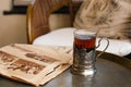 A glass in an antique cup holder with tea and old newspaper are on a copper table Royalty Free Stock Photo