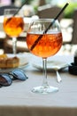 A glass of aperol spritz or campari orange cocktail with orange slice and ice on a restaurant table on the seashore on a sunny day Royalty Free Stock Photo