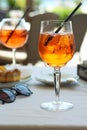 A glass of aperol spritz or campari orange cocktail with orange slice and ice on a restaurant table on the seashore on a sunny day Royalty Free Stock Photo