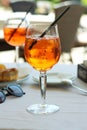 A glass of aperol spritz or campari orange cocktail with orange slice and ice on a restaurant table on the seashore on a sunny day Royalty Free Stock Photo