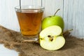 A glass of apple juice and a green apple on a white wooden background. Royalty Free Stock Photo