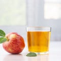 Glass of apple juice and ripe red apples with leaves.