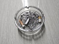 Glass ashtray with circle shape lying on the floor with cigarette butts and ashes in it Royalty Free Stock Photo