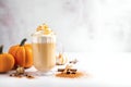 Glass of autumn pumpkin latte with whipped cream and cinnamon over blurred light grey background. Coffee with pumpkin and spices