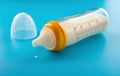 A glass baby bottle with powdered milk on blue background Royalty Free Stock Photo