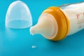 Glass baby bottle with powdered milk on blue close up
