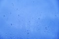 Glass background with big drops of rain. Autumn window with the texture of water drops against a cloudy blue sky Royalty Free Stock Photo