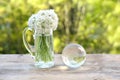 glass ball globe, bouquet of wild garlic flowers on old wooden table in garden, beautiful blurred natural landscape in background Royalty Free Stock Photo