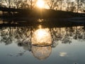 Glass ball on the hand, against the backdrop of a beautiful sunset. Sunset water. Reflection in water