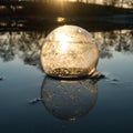 Glass ball on the hand, against the backdrop of a beautiful sunset. Sunset water. Reflection in water