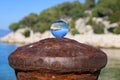 Glass ball lying on a rusty bollard
