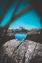 A glass ball on rock formation near a lake with the reflection of rocky mountains and the blue sky