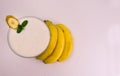 A glass of banana smoothie and a branch of bananas on a white background.Top view. Copy space.