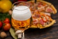 Glass of beer and appetizing pizza with salami on background Royalty Free Stock Photo