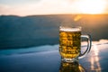 Glass of beer on a beach at sunset. Cooling summer drink concept. Close Up of A Glass of Draught Beer with the Bokeh of Sunlight Royalty Free Stock Photo