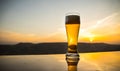 Glass of beer on a beach at sunset. Cooling summer drink concept. Close Up of A Glass of Draught Beer with the Bokeh of Sunlight Royalty Free Stock Photo