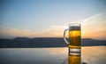 Glass of beer on a beach at sunset. Cooling summer drink concept. Close Up of A Glass of Draught Beer with the Bokeh of Sunlight Royalty Free Stock Photo