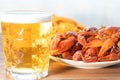 A glass of beer , boiled crayfish and a plate of nachos chips on the table, close up Royalty Free Stock Photo