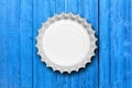 Glass beer bottle cap isolated on blue wooden background, top view. 3d illustration Royalty Free Stock Photo