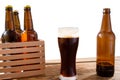 Glass of beer and bottles with no logo on wooden table isolated copy space, glass bottle Royalty Free Stock Photo