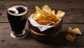 A glass of beer and a bowl of potato chips on a wooden table Royalty Free Stock Photo