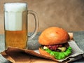 A glass of beer and a cheeseburger on a craft paper