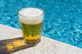 Glass of beer on concrete patio and blurry swimming pool background Royalty Free Stock Photo