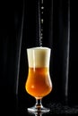 Glass of beer on dark background. beer being poured into glass Royalty Free Stock Photo