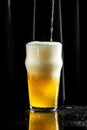 Glass of beer on dark background. beer being poured into glass Royalty Free Stock Photo