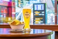 A glass of beer Edelweiss and a plate of breadcrumbs and cheese. In the background, online board displays flights to the airport.