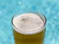 Glass of beer on edge by poolside Royalty Free Stock Photo