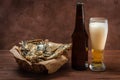 A glass of beer with foam, a bottle and a basket of fish Royalty Free Stock Photo