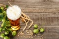 Glass beer glass with foam with hops cones, barley grains and wheat ears on dark wooden table background with copy space, top view Royalty Free Stock Photo