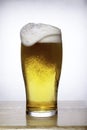 Glass of beer with foam overflowing on white