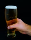 Glass of beer in hand on a black background Royalty Free Stock Photo