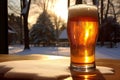 A glass of beer with beer head, view of resort and pine trees with snow, sunrising in winter morning, close up shot with copy Royalty Free Stock Photo