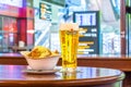 Glass of beer Heineken and plate of breadcrumbs and cheese. In the background, online board displays flights to the airport. Russi