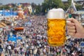 Glass of beer holding in hand at Oktoberfest in Munich Royalty Free Stock Photo