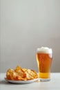 A glass of beer is next to a plate of chips Royalty Free Stock Photo