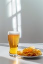 A glass of beer is next to a plate of chips Royalty Free Stock Photo