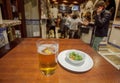 Glass of beer and olives on table of busy bar with drinking people Royalty Free Stock Photo