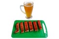 Glass of beer and pieces of red salmon fish on a green chopping board Royalty Free Stock Photo