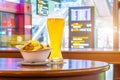 A glass of beer and a plate of breadcrumbs and cheese. In the background, online board displays flights to the airport. Concept ex